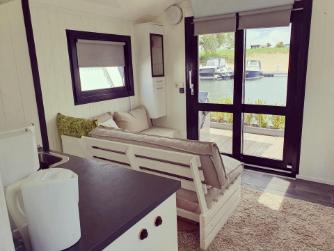 Interno di una houseboat al Rhederlaagse Meren, Paesi Bassi, con vista sul porto turistico dalle vetrate.