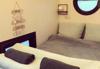 Camera accogliente con letto rifatto e asciugamani arrotolati in una houseboat al Rhederlaagse Meren, Paesi Bassi.