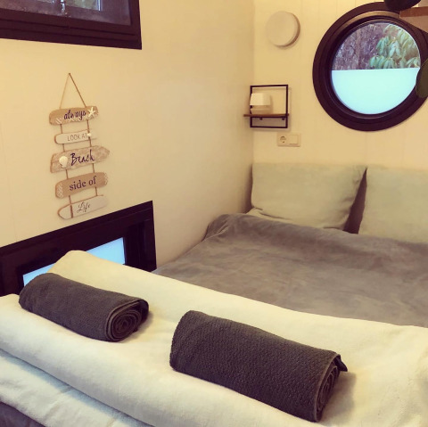 Camera accogliente con letto rifatto e asciugamani arrotolati in una houseboat al Rhederlaagse Meren, Paesi Bassi.