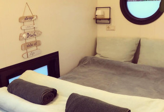 Camera accogliente con letto rifatto e asciugamani arrotolati in una houseboat al Rhederlaagse Meren, Paesi Bassi.