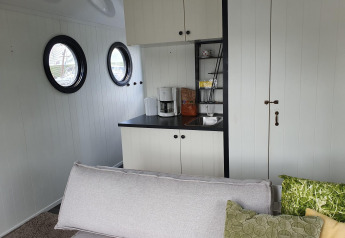 Modernes Wohnzimmer mit Kochnische, Sofa, Bullaugen und Kaffeemaschine auf einem Hausboot bei Rhederlaagse Meren.