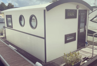 Woonboot aan de aanlegsteiger van Marina Rhederlaagse Meren, Nederland, met wolkenlucht erboven.