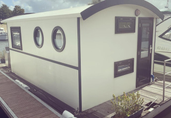 Houseboat attraccata al parco ricreativo e marina Rhederlaagse Meren nei Paesi Bassi sotto cielo nuvoloso.