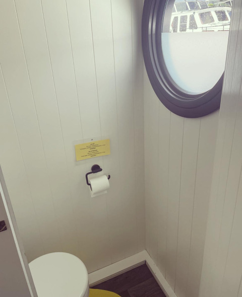 Toilette mit rundem Bullauge auf Hausboot im Recreation park und Marina Rhederlaagse Meren, Niederlande.