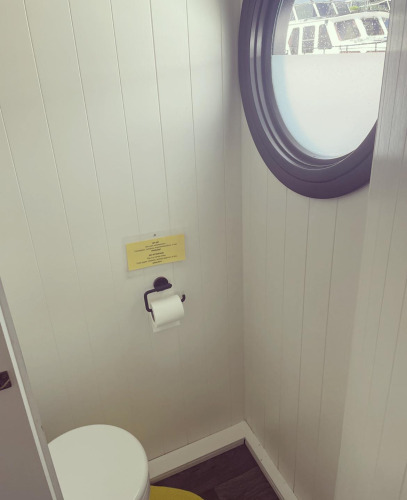 Toilet with round porthole window on a houseboat at Recreation park and Marina Rhederlaagse Meren, Netherlands.
