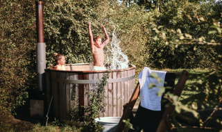 Børn nyder en udendørs træbadekar ved Feather Down De Kalverweide feriepark i Overijssel, Holland.