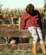 Barn i rød sweater og gule gummistøvler læner sig op ad hegn med gris på Feather Down De Kalverweide.