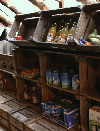 Træhylder med lokale fødevarer, frugter, æg og drikkevarer i butikken på Feather Down De Kalverweide.