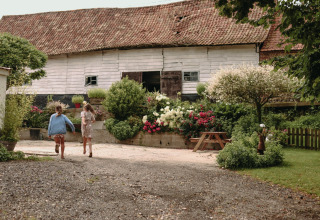 To børn løber foran en rustik lade med have og blomster ved Feather Down Fermette des trois tilleuls, Hauts-de-France.