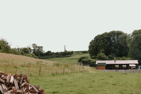 Landskabsbillede nær Bezinghem i Hauts-de-France med en lade, grønne marker og skov i baggrunden.