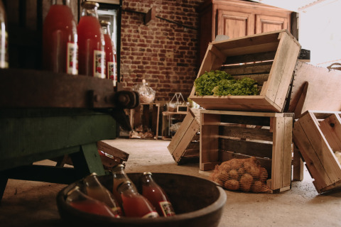 Farm storage with wooden crates of vegetables, potatoes in netting, and bottles at Feather Down Fermette.