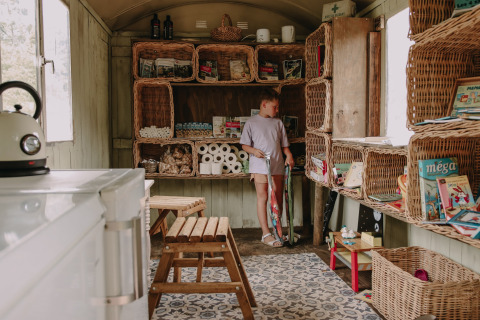Niño en sala con cestas de mimbre en Feather Down Fermette des trois tilleuls, Hauts-de-France, Francia.