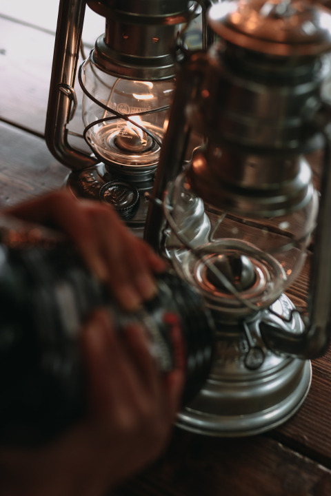 A person operates an oil lantern on a wooden table at Feather Down Fermette des trois tilleuls, France.