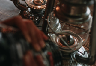 Eine Person bedient eine Petroleumlampe auf einem Holztisch im Feather Down Fermette des trois tilleuls, Frankreich.