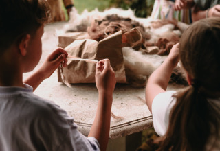 Bambini che lavorano la lana a un tavolo al Feather Down Fermette des trois tilleuls, Hauts-de-France, Francia.