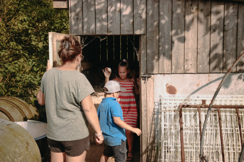 Una mujer y dos niños exploran un granero en Feather Down Fermette des trois tilleuls, Hauts-de-France.