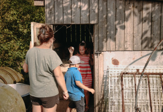 A woman and two children explore a barn at Feather Down Fermette des trois tilleuls in Hauts-de-France.