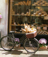 Una bicicleta con una cesta llena de baguettes frente a una panadería que exhibe pan fresco en Bezinghem, Francia.