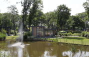 Udsigt over en hyggelig lodge ved en dam med springvand på Landgoed de Scheleberg i Holland.