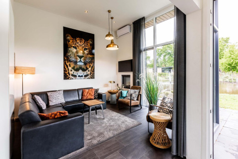 Gezellige woonkamer in Z Module op Landgoed de Scheleberg met luipaardkunst en hoge raampartijen.