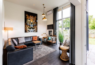 Gezellige woonkamer in Z Module op Landgoed de Scheleberg met luipaardkunst en hoge raampartijen.