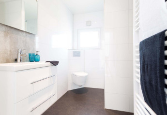 Salle de bain moderne et lumineuse du Z Module à Landgoed de Scheleberg, aux Pays-Bas, avec WC suspendu blanc.