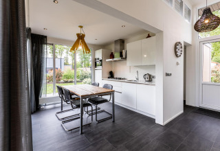 Modern kitchen and dining area at Z Module, Landgoed de Scheleberg, Netherlands, with large windows and garden view.