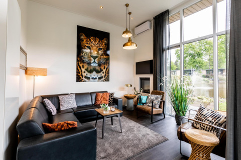 Lichte, moderne woonkamer in Z Module lodge op Landgoed de Scheleberg, Nederland, met opvallende luipaardkunst.