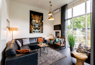 Lichte, moderne woonkamer in Z Module lodge op Landgoed de Scheleberg, Nederland, met opvallende luipaardkunst.