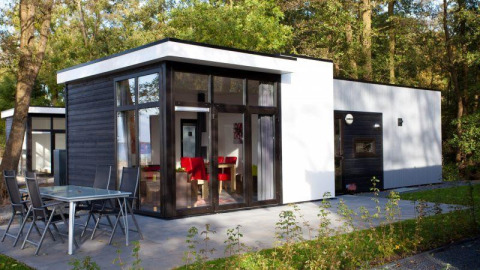 Lodge Cube la Mer 4 à Schoneveld, Pays-Bas, moderne et vitrée, avec terrasse extérieure au cœur de la forêt.