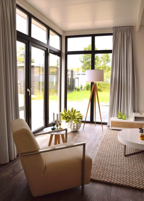 Salón moderno en la cabaña Cube la Mer 4 de Schoneveld, Países Bajos, con grandes ventanales y decoración elegante.