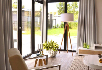 Moderne woonkamer in Cube la Mer 4 lodge in Schoneveld, Nederland, met veel lichtinval en stijlvolle inrichting.