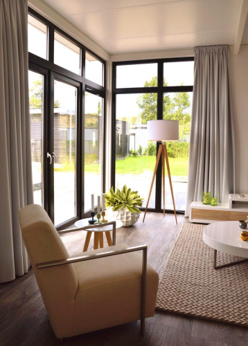 Modern living room at Cube la Mer 4 lodge in Schoneveld, Netherlands, featuring large windows and chic decor.