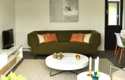 Sala moderna en Cube la Mer 4 lodge, Schoneveld, Países Bajos, con sofá verde y decoración elegante.