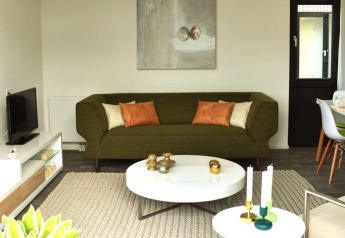 Moderne woonkamer in Cube la Mer 4 lodge, Schoneveld, Nederland, met groene zetel en stijlvolle inrichting.