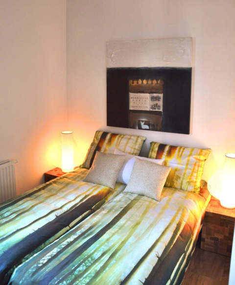 Modernes Schlafzimmer mit Waldmotiv-Bettwäsche, warmem Licht und Kunstwerk in Cube la Mer 4 in Schoneveld.