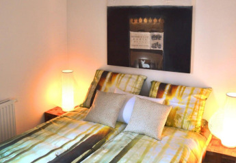 Dormitorio moderno en Cube la Mer 4 en Schoneveld, Países Bajos, con ropa de cama de bosque y lámparas cálidas.