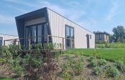 Moderne lodge Just Nature Light ved Marina Strandbad i Holland på en solrig dag med grønne omgivelser.