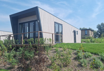 Moderne Just Nature Light lodge bij Marina Strandbad in Nederland, omringd door zon en groene tuin.