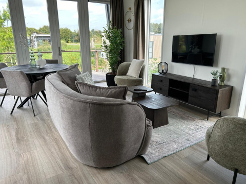 Modernes Wohnzimmer in der Just Nature Light Lodge im Marina Strandbad, Niederlande, mit großem Fensterblick.
