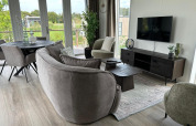 Moderne stue i Just Nature Light-lodge ved Marina Strandbad, Holland, med store vinduer og hyggeligt interiør.