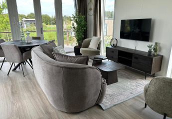 Moderne stue i Just Nature Light-lodge ved Marina Strandbad, Holland, med store vinduer og hyggeligt interiør.