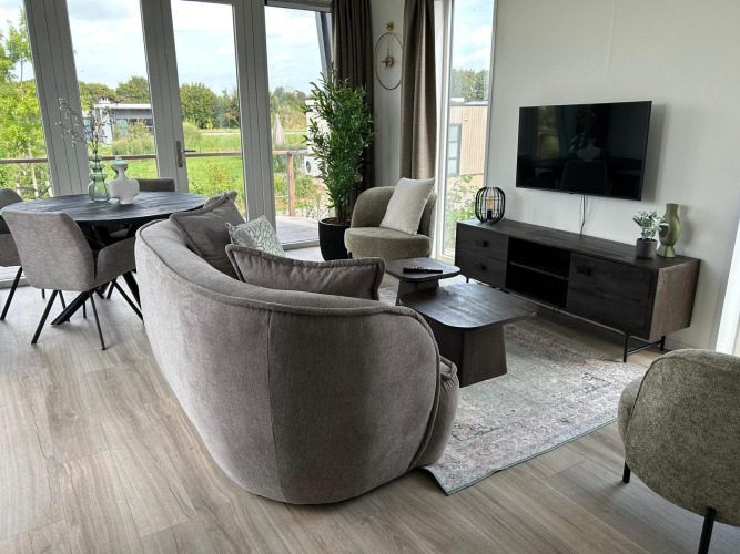 Salón moderno en Just Nature Light Lodge, Marina Strandbad, Países Bajos, con grandes ventanas y decoración acogedora.