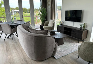 Moderne woonkamer in Just Nature Light lodge, Marina Strandbad, Nederland, met grote ramen en knusse sfeer.