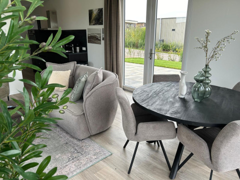 Moderne woonkamer in Just Nature Light lodge bij Marina Strandbad, Nederland, met knusse zetels en tuinzicht.