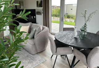 Moderne stue i Just Nature Light-lodge ved Marina Strandbad, Nederlandene, med bløde møbler og udsigt til have.