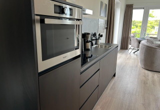 Moderne keukenhoek met oven en koffiezet in Just Nature Light lodge aan Marina Strandbad, Nederland.