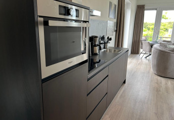 Moderne keukenhoek met oven en koffiezet in Just Nature Light lodge aan Marina Strandbad, Nederland.