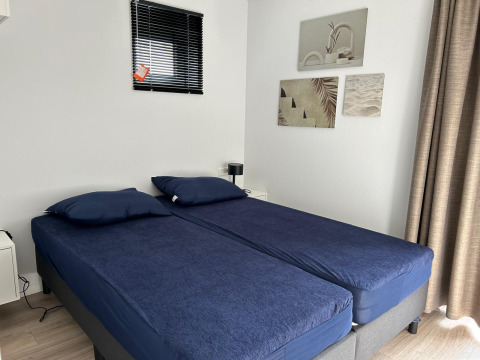 Modern lodge bedroom Just Nature Light at Marina Strandbad Netherlands, twin beds, navy bedding, wall art.