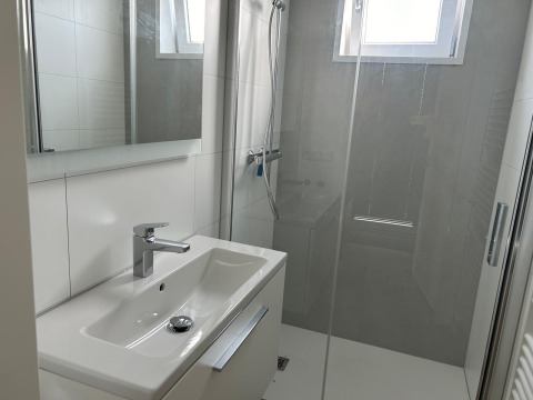Bagno moderno e luminoso con lavabo, specchio e doccia al Just Nature Light, Marina Strandbad, Paesi Bassi.